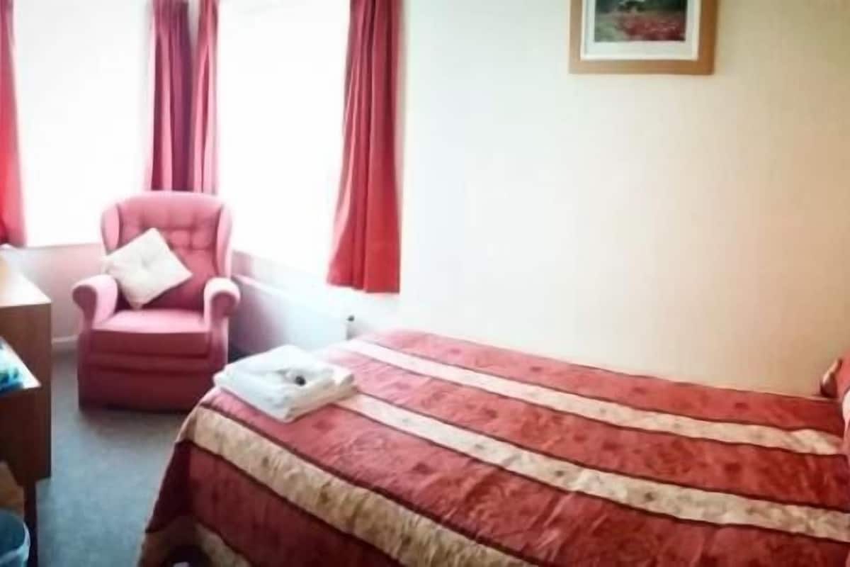 A hotel room with a bed, a chair, and a small table.