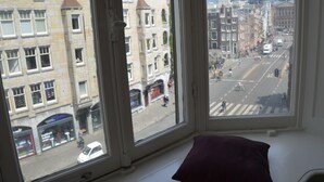 A view from a window with a view of a city street, buildings, and a crosswalk.