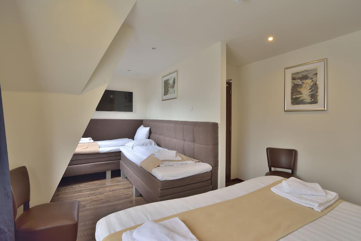 Una habitación de hotel con una cama grande, una cama más pequeña, un escritorio y una silla.