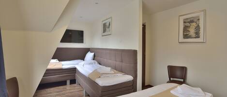 A hotel room with a large bed, a smaller bed, a desk, and a chair.