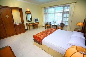 A hotel room with a large bed, a desk with a chair, a television, and a wardrobe. - Pondok Serrata Convention, Boutique & Tourist Hotel (Semarang)