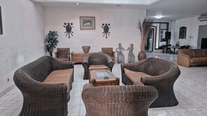 A spacious living area with wicker furniture, a coffee table, and decorative wall art. - Pondok Serrata Convention, Boutique & Tourist Hotel (Semarang)