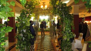 A corridor with a patterned floor, a chandelier, and a crowd of people.