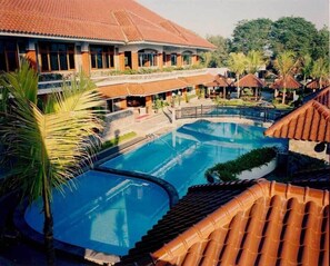 Un resort con una amplia piscina, palmeras y un edificio de techo a ladrillo.