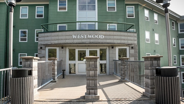 A building with a sign reading "WESTWOOD" at the entrance, featuring a stone facade, multiple windows, and a gated entrance. - Mount Saint Vincent University Residence - Hostel (Halifax)