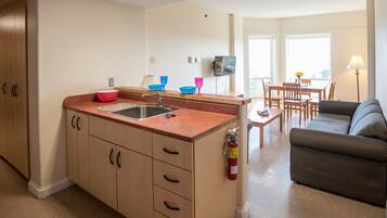 A compact kitchen with a sink, a dining area with a table and chairs, and a sofa.