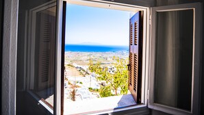 An open window with a view of a coastal landscape, including a body of water and distant land.