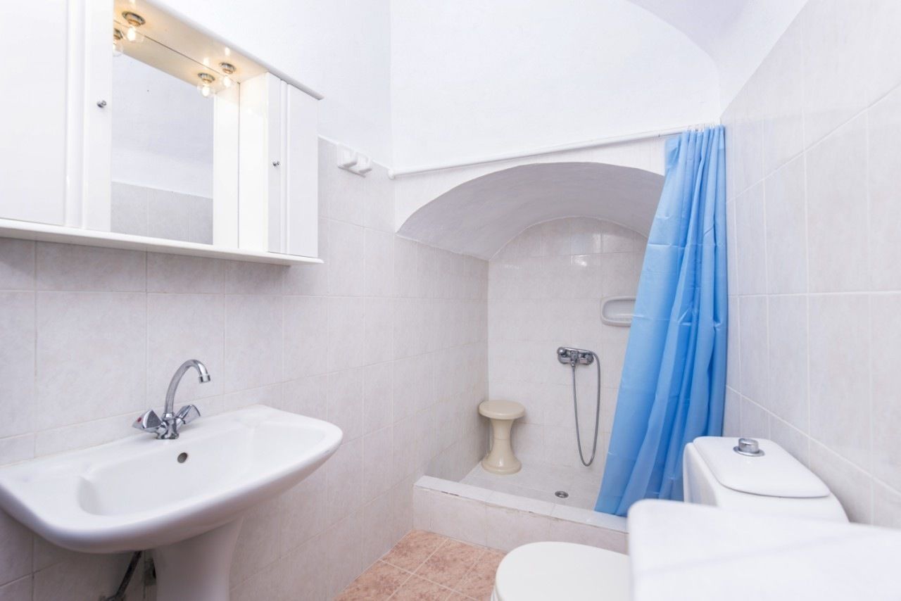 Un baño con lavamanos, inodoro y zona de ducha.