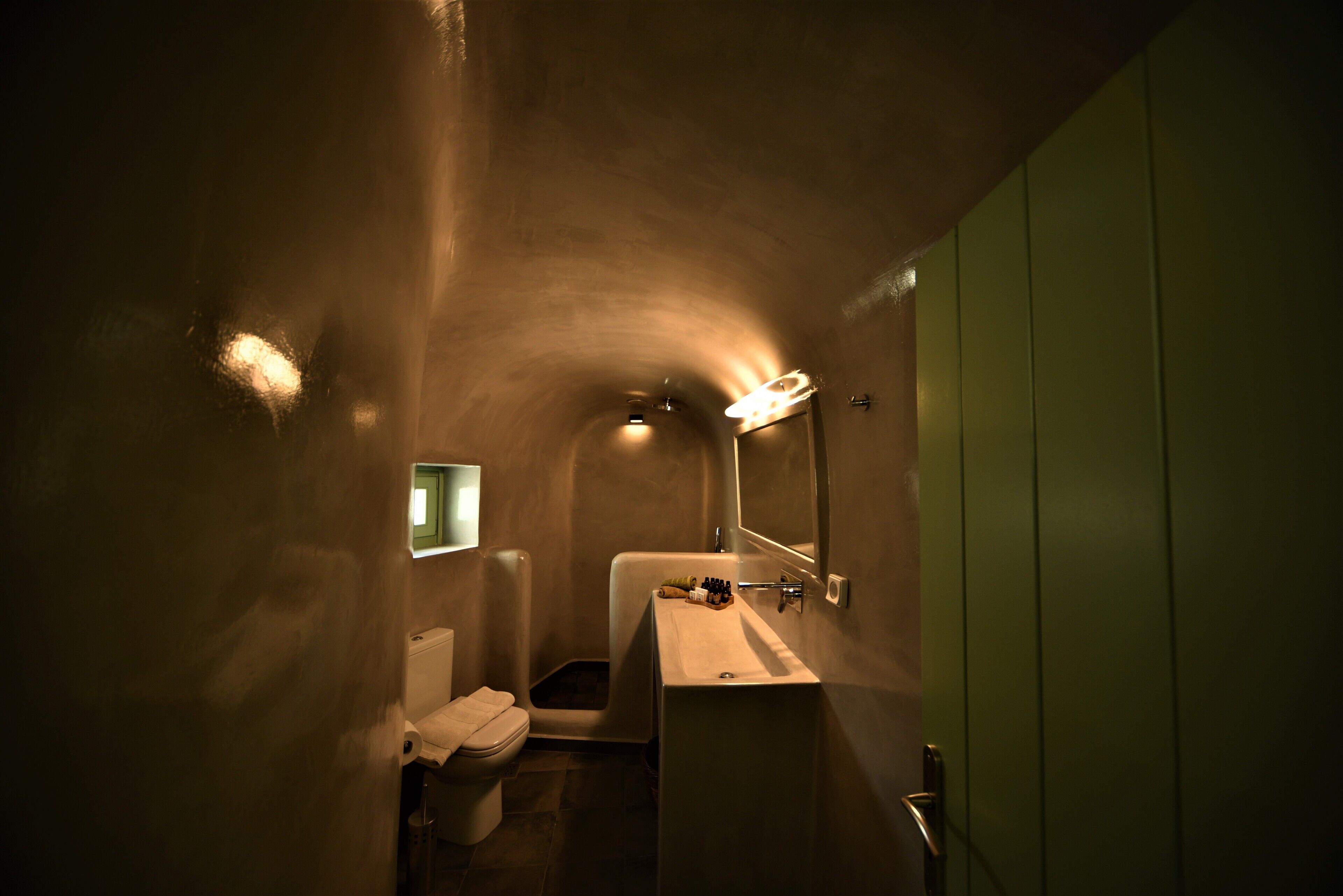 A compact bathroom with a toilet, sink, and mirror.