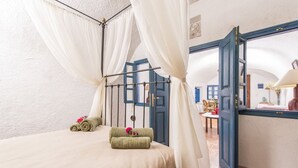A bedroom with a bed, a canopy, and a view of the dining area.
