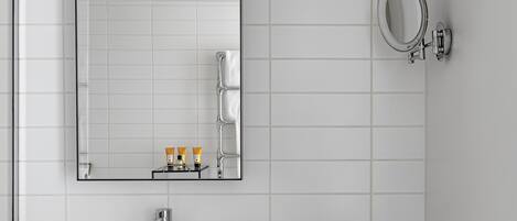A modern bathroom with a white sink, mirror, and tiled walls.