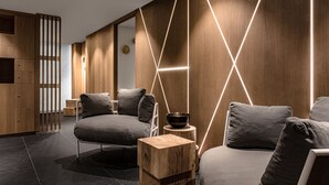 A modern room with a sofa, a wooden sideboard, and a geometric light installation on the wall. - White 1921 Courchevel (Courchevel)