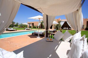 Una piscina al aire libre, sombrillas, tumbonas