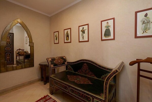 A traditional room with a sofa, a mirror, and framed artwork on the wall.