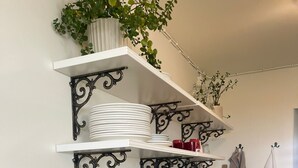 A kitchen with white marble countertops, black metal shelves, and a hanging utensil rack. - Crafoord Place - Hostel (Stockholm)