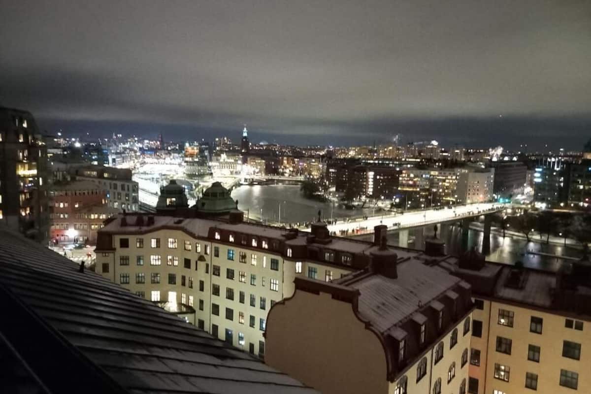 A nighttime cityscape with buildings, a river, and a bridge.