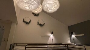 A bunk bed with a headboard, a bedside lamp, and a wall-mounted light fixture. - Crafoord Place - Hostel (Stockholm)