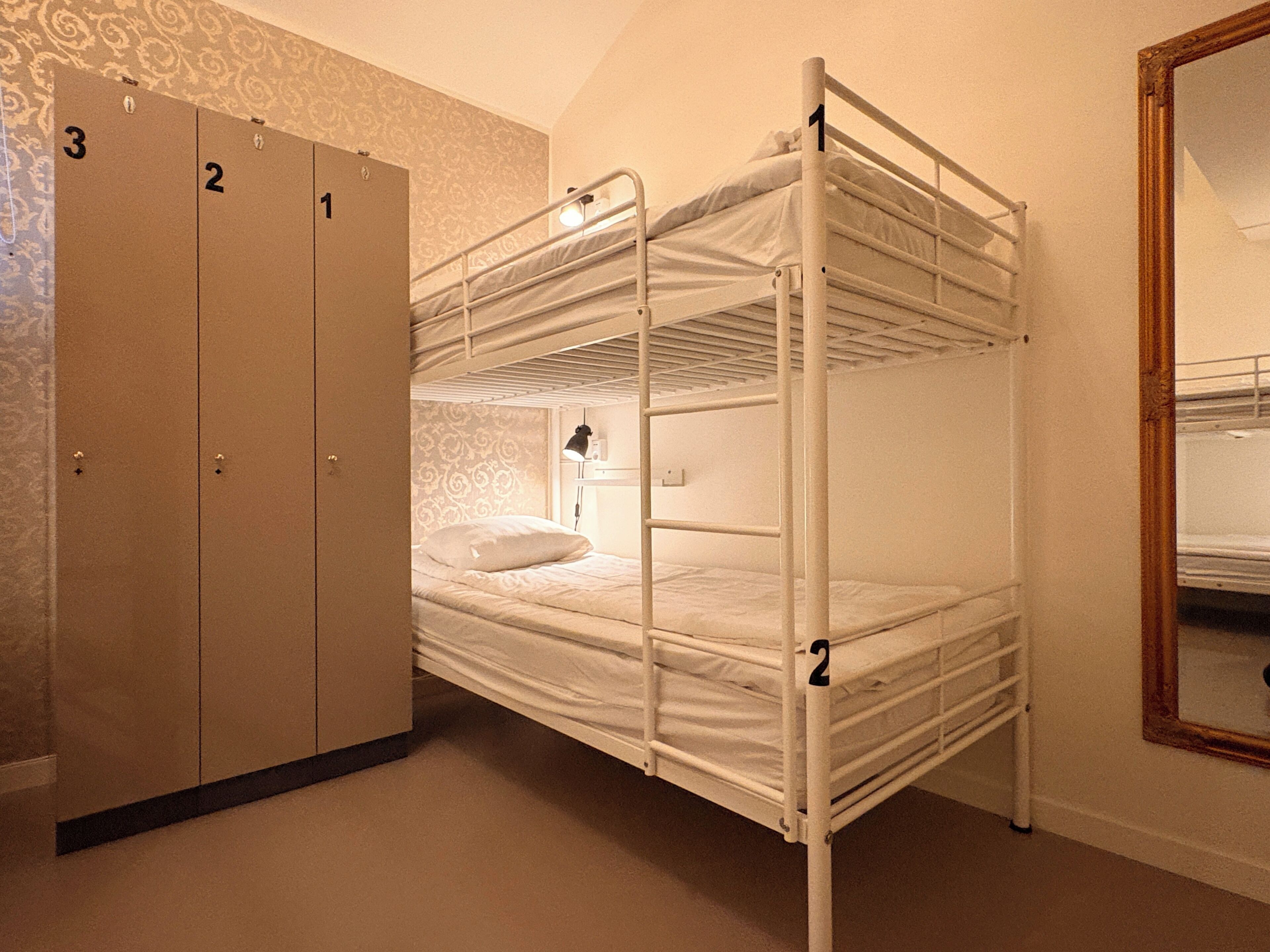 Een slaapkamer met een stapelbed, een garderobe en een spiegel.