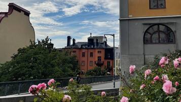 En byggnad med en röd fasad och ett grönt tak, omgiven av träd och en bro med rosa blommor.
