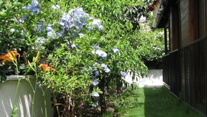 A garden with a variety of plants and flowers, a white wall, and a black fence. - Kybele Hotel (Fethiye)
