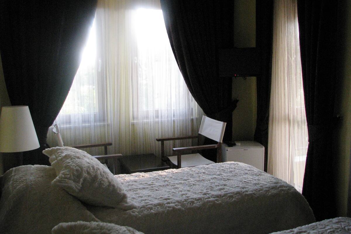 Una habitación de hotel con una cama, dos sillas, un escritorio y una lámpara.