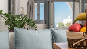 Una sala de estar moderna con un sofá, una planta en maceta y una cesta de frutas sobre una mesa de madera.