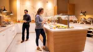 A modern kitchen with a buffet setup, including a variety of food items and a map on the wall. - Hotel Hafenspeicher (Leer)