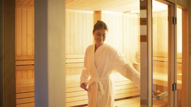 A sauna room with wooden benches and a glass door. - Hotel Hafenspeicher (Leer)