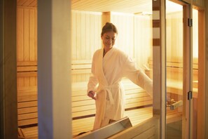 Un sauna con bancos de madera y una puerta de vidrio.
