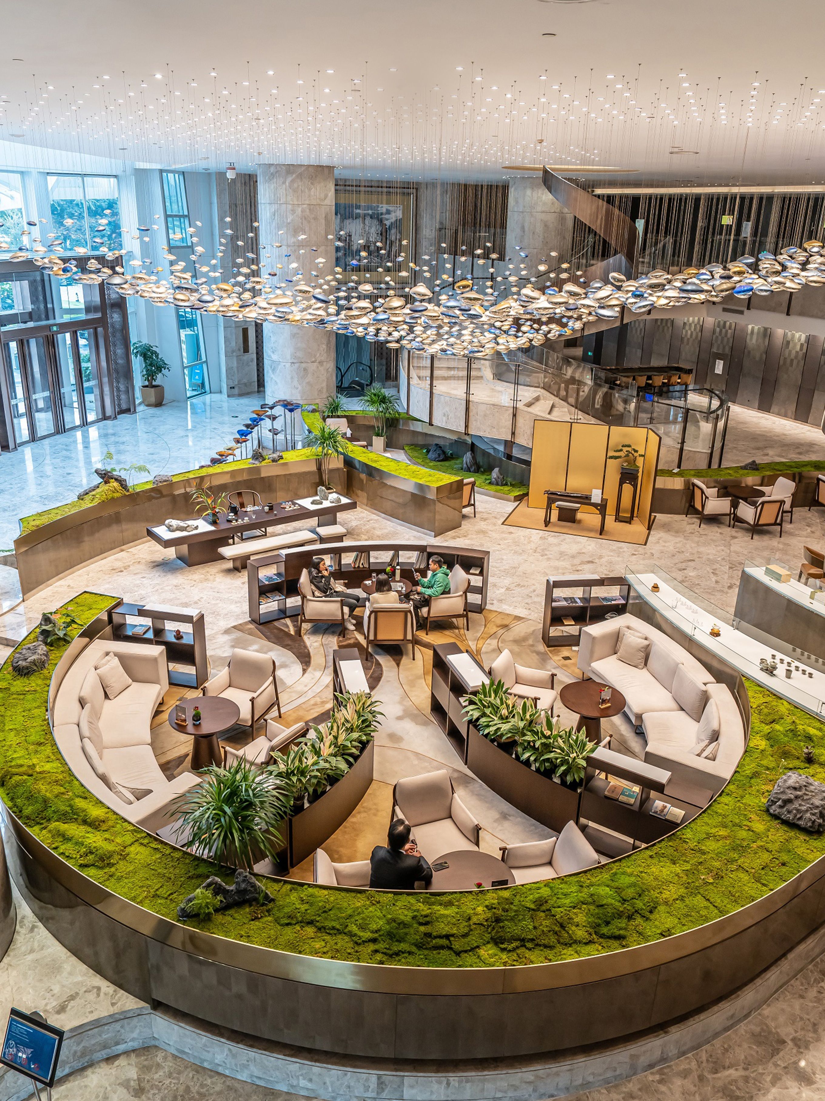 A spacious lobby with a central seating area, a reception desk, and a staircase leading to upper floors.