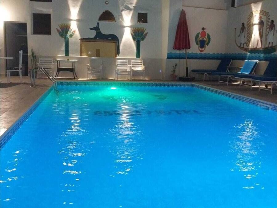 Une piscine avec des chaises longues et une fresque murale.