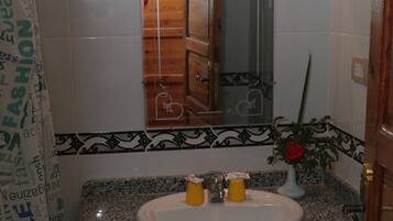 Baño con lavamanos de encimera de granito, espejo y cesta verde.