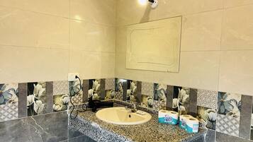 Un baño con encimera de granito, lavabo y papel higiénico.