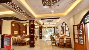 A spacious dining area with multiple tables and chairs, decorative pillars, and a modern ceiling design. - Amon Hotel (Luxor)