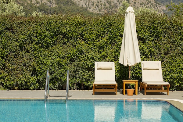 Una piscina al aire libre, sombrillas, sillones reclinables de piscina