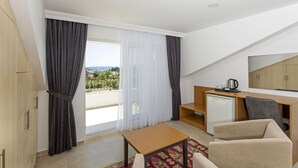 A hotel room with a balcony, a desk with a refrigerator, a sofa, and a small table. - Kerem Apart Hotel Gocek (Fethiye)