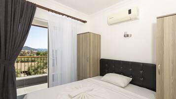Una habitación de hotel con cama, armario, aire acondicionado y vistas al exterior.