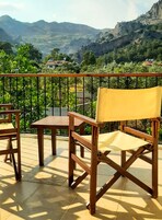 Un balcón con una mesa y dos sillas, con vistas a un paisaje montañoso.