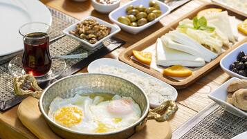 A breakfast spread with various foods and a glass of tea on a wooden table.
