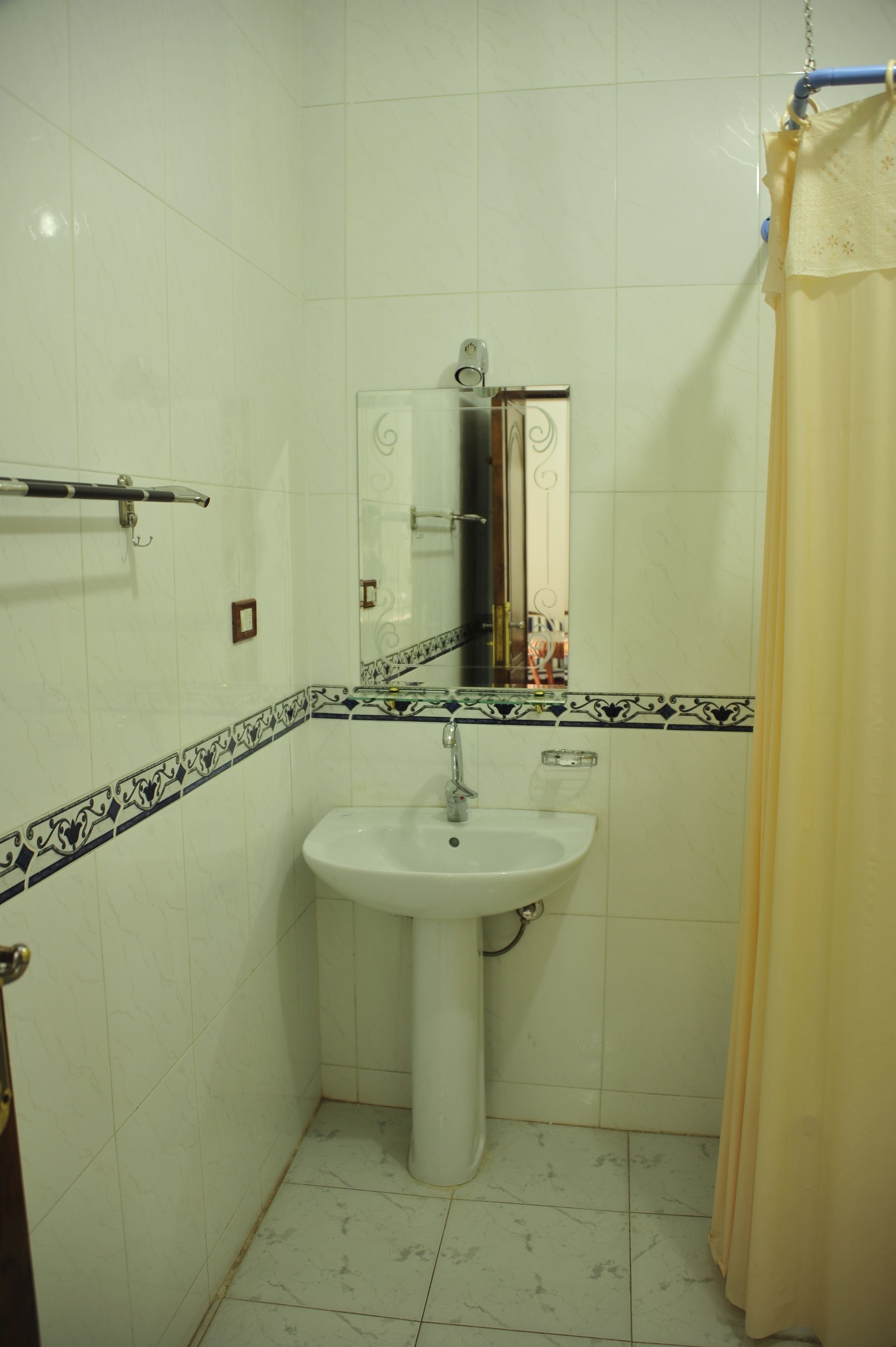 Een badkamer met een wastafel op voet, een spiegel en een douchegordijn.