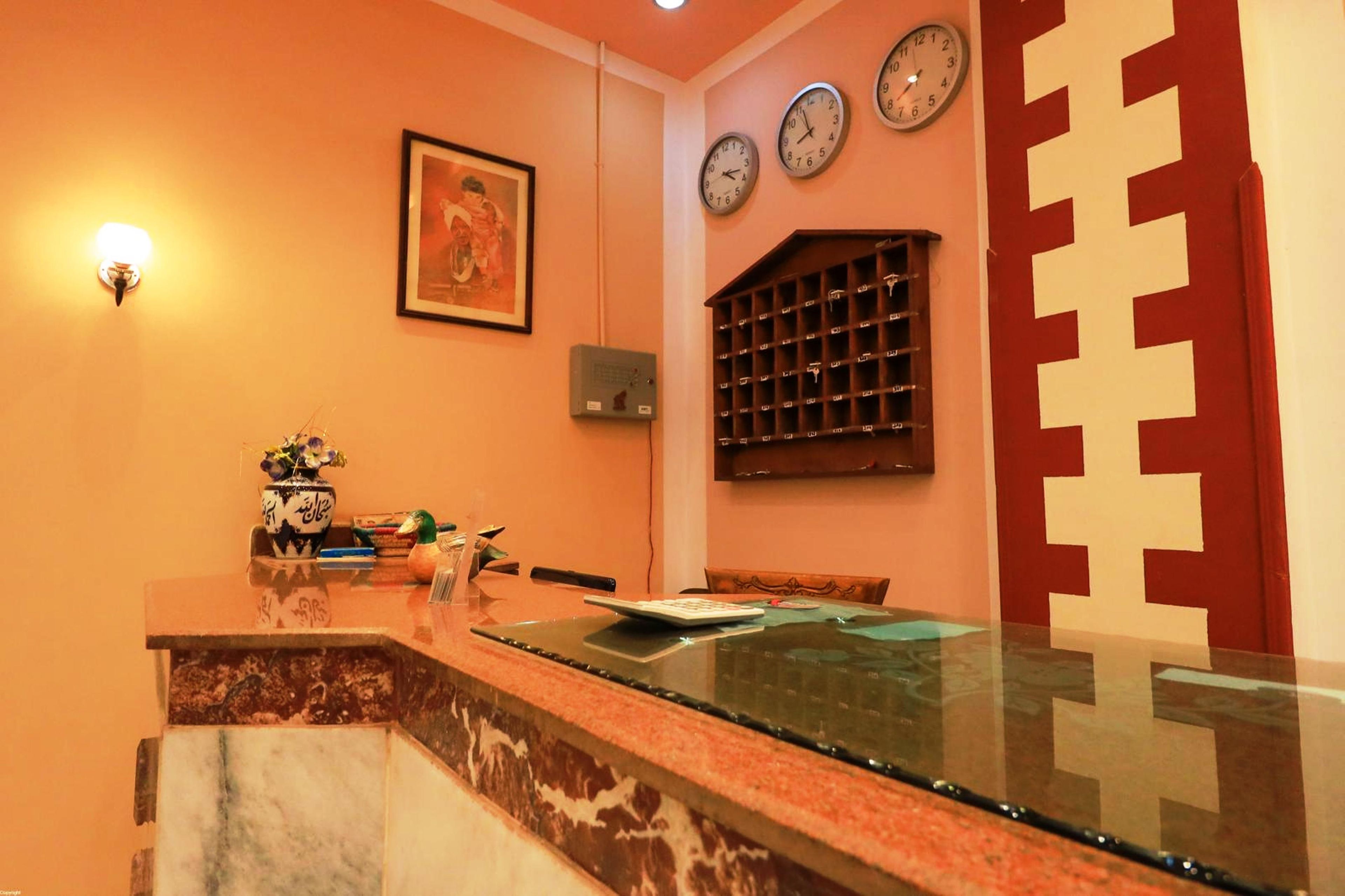 A reception area with a marble counter, a framed picture on the wall, and three wall clocks.