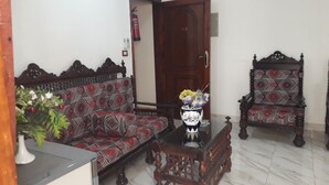 A living room with a sofa, a coffee table, and a patterned armchair.