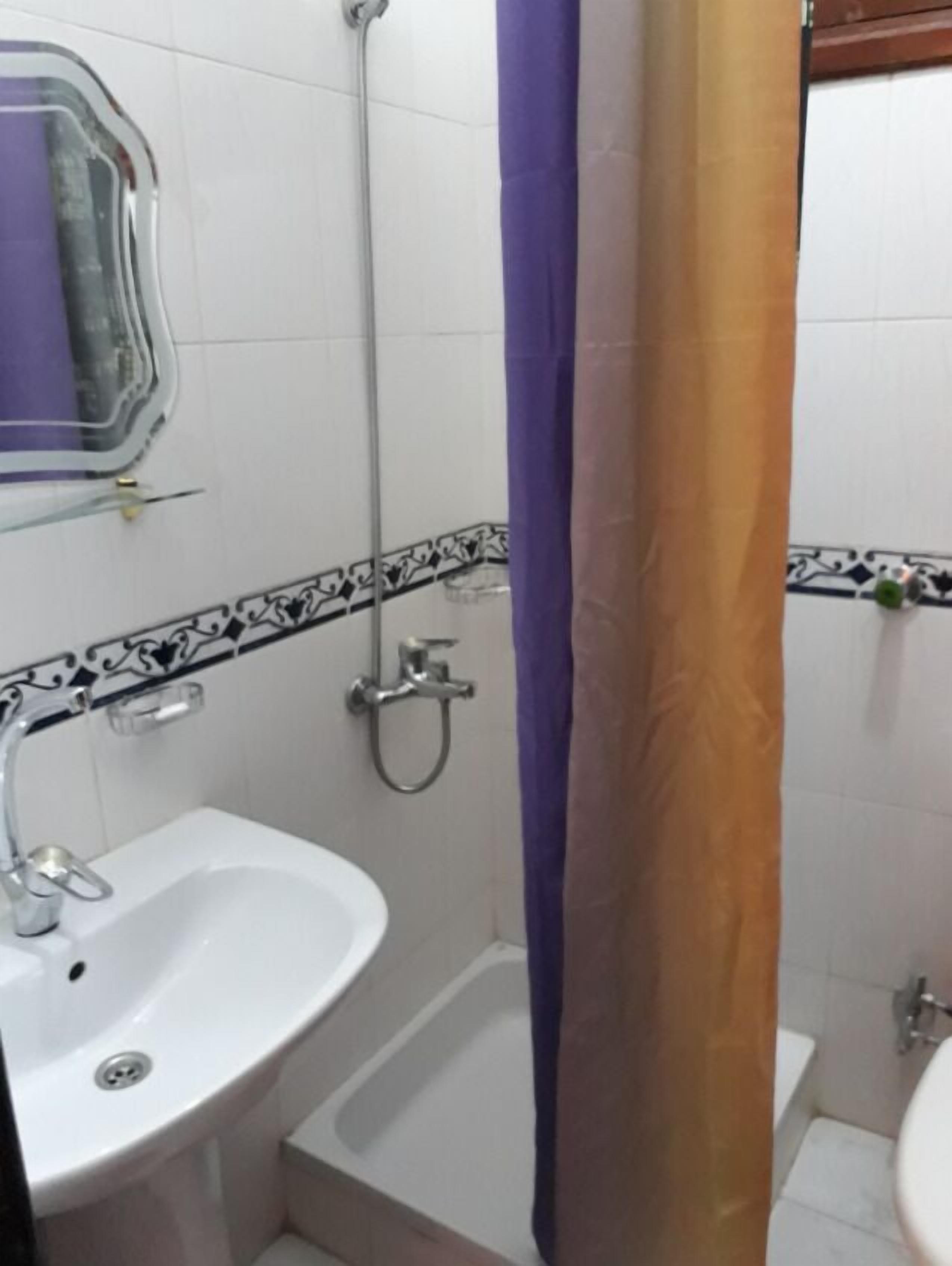 A bathroom with a white sink, a shower, and a toilet.