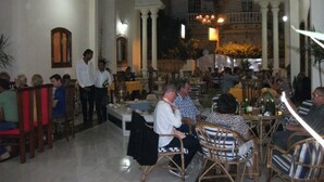 A spacious indoor dining area with high ceilings and classical architecture, featuring multiple dining tables and chairs.