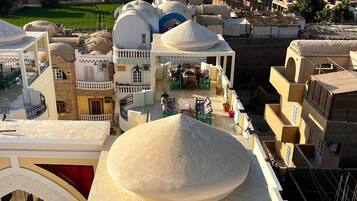 Un bâtiment à plusieurs étages, doté d’un dôme central et entouré d’autres structures, le tout se dressant sur fond de montagnes.