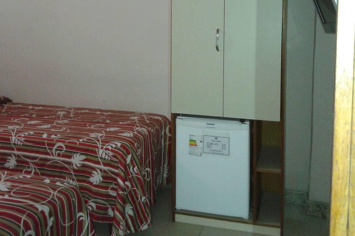 Una habitación pequeña con una cama, un armario y un refrigerador.