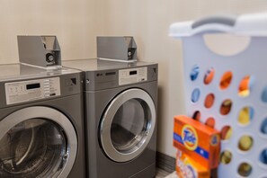 A laundry area with two front-loading washing machines and a wall-mounted dryer. - Hampton Inn & Suites West Des Moines/SW Mall Area (West Des Moines)