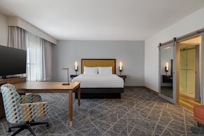 A hotel room with a bed, a desk, a TV, a chair, and a sliding door. - Hampton Inn & Suites West Des Moines/SW Mall Area (West Des Moines)