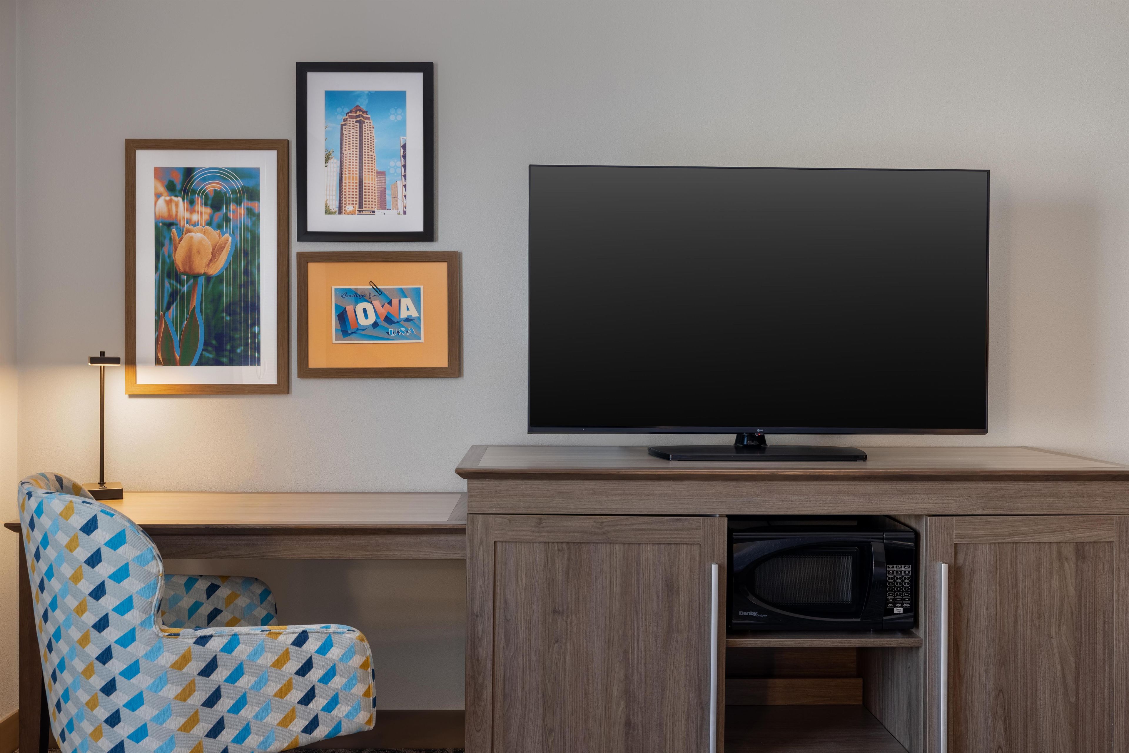 A modern living room with a flat-screen TV, a microwave, and a patterned armchair.