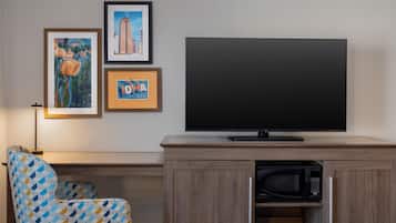 A modern living room with a flat-screen TV, a microwave, and a patterned armchair.
